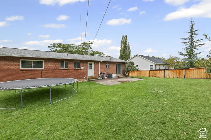 Exterior of red brick home featuring a concrete patio, wood privacy fencing, and expansive lawn space