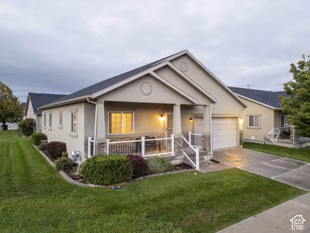Single-story residence with stucco and stone veneer siding, covered front porch, white railing, and attached garage