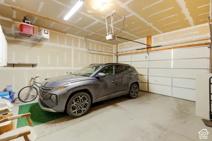 2 car garage featuring a concrete floor, motorized sectional overhead door, overhead storage shelving, and automatic door opener