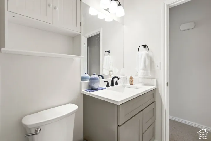 Bathroom featuring a grey vanity with a stone countertop, an integrated rectangular sink, a matte black faucet, and built-in upper cabinetry