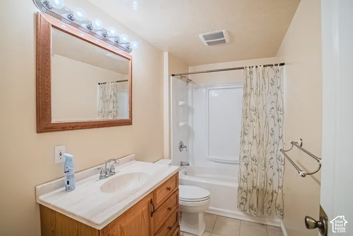 Bathroom featuring a wood-toned vanity with an integrated countertop and sink, chrome fixtures, a framed wall mirror, and a tub-shower combination with a surround