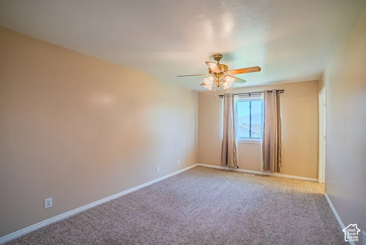 Neutral wall tones, wall-to-wall carpeting, and a multi-light ceiling fan