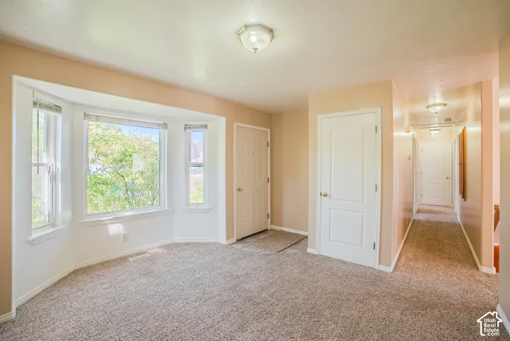 Bay window, neutral wall palette, carpeting, flush-mount lighting, and solid-core interior doors