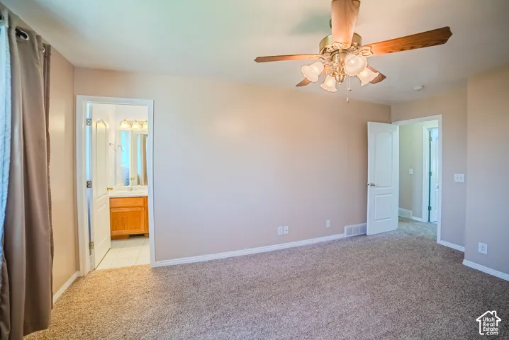 Room featuring neutral-toned walls, neutral carpeting, a multi-blade ceiling fan with integrated lighting, and white paneled interior doors