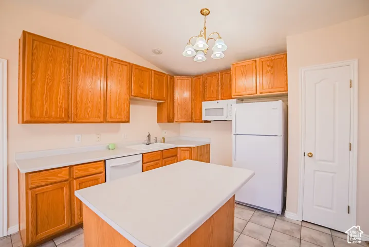 Kitchen featuring natural wood cabinetry, central island, tiled flooring, integrated white appliances, and a multi-light chandelier