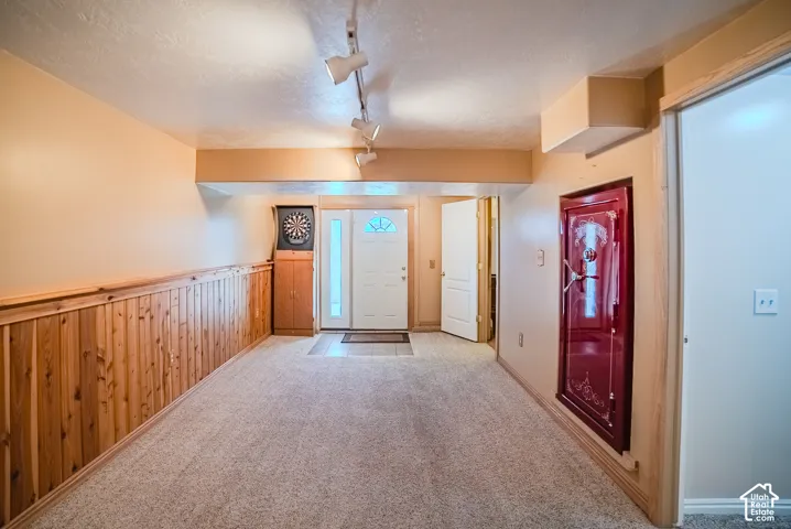 Interior space featuring wood-paneled walls, neutral carpeting, a built-in wall safe, and adjustable track lighting