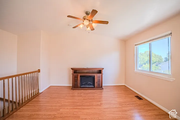 Wood-finish flooring, vaulted ceiling, built-in electric fireplace console, ceiling fan with light kit, and double-pane window