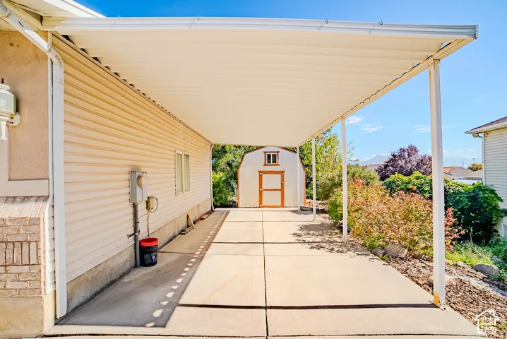 Covered carport featuring a concrete pad and a detached storage shed