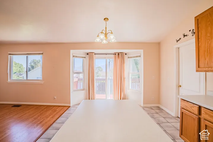 Wood-finish flooring, central kitchen island with solid-surface countertop, bay window configuration, and multi-light brass chandelier
