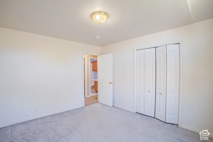 Neutral-toned carpeting, white bi-fold closet doors, arched-panel interior door, and a flush-mount ceiling light fixture
