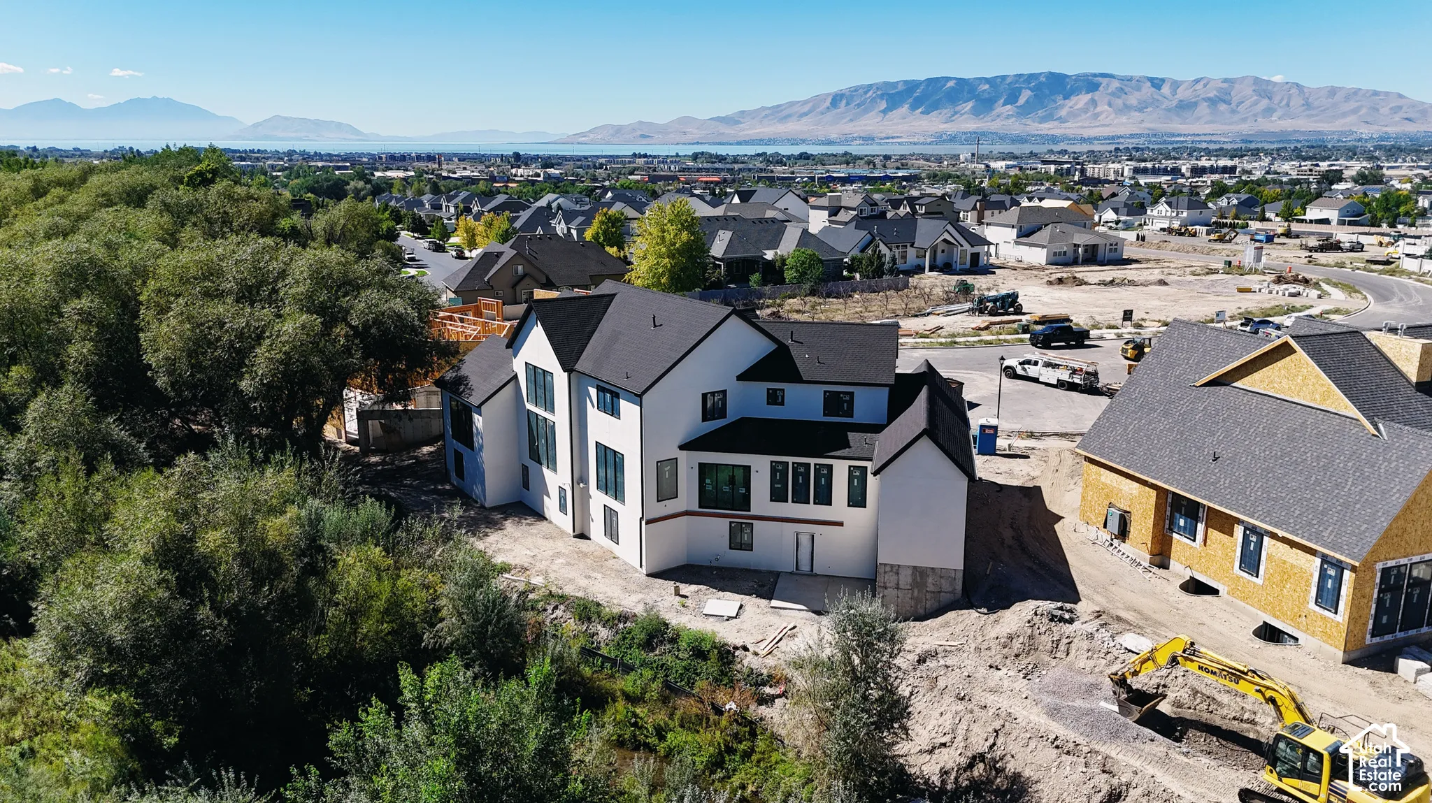 Two-story exterior featuring a white smooth-finish facade, dark roofline, expansive window placement, and mountain backdrop