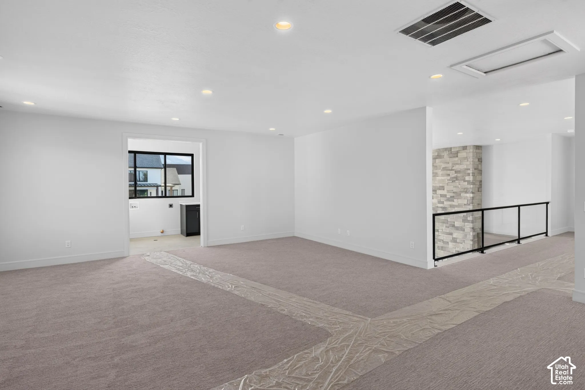 Open interior featuring recessed lighting, a stone-accented wall, and a metal-framed railing