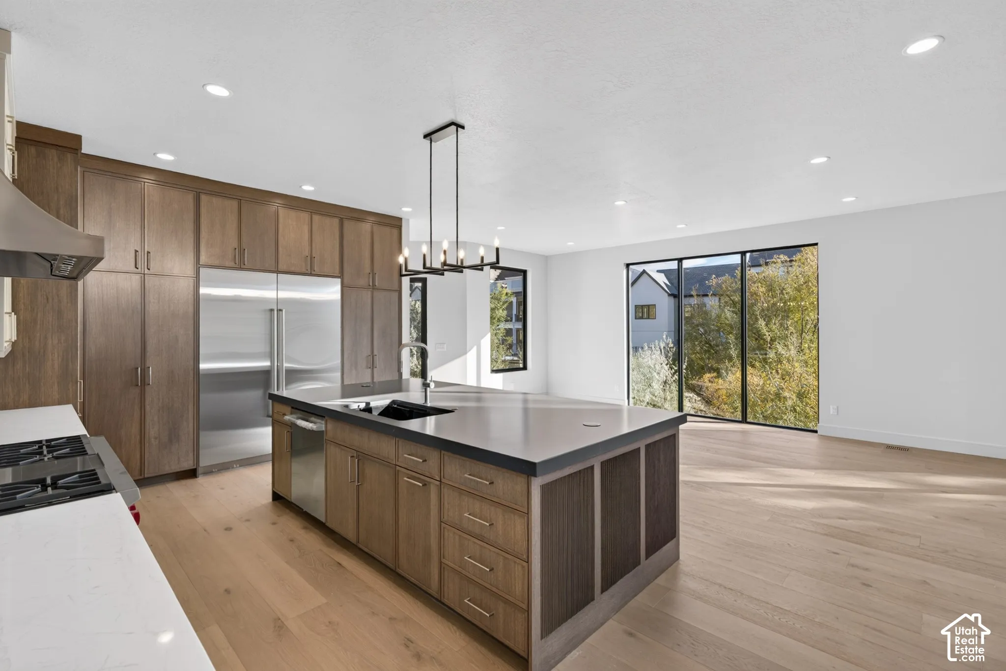 Kitchen featuring floor-to-ceiling wood cabinetry, a central island with a solid-surface countertop, wood-finish flooring, recessed lighting, and a floor-to-ceiling glass panel