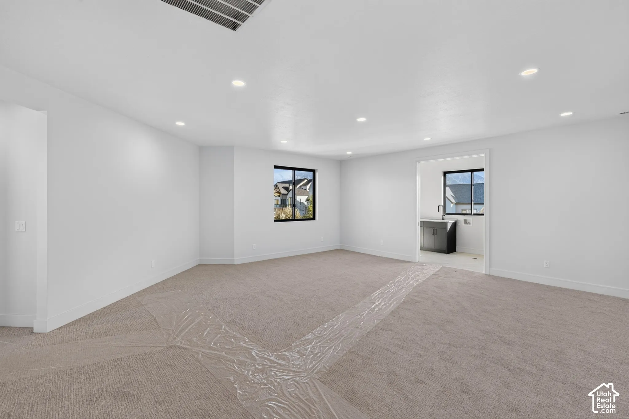 Open floor plan featuring recessed lighting, neutral wall-to-wall carpeting, and dark-framed windows