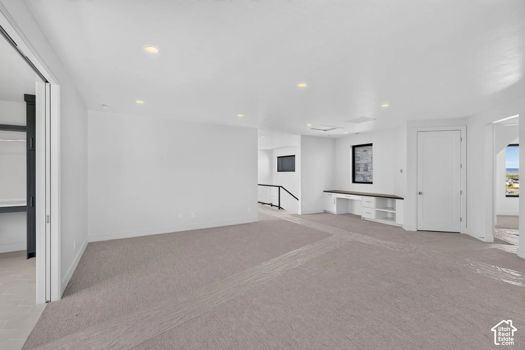 Open interior space featuring recessed ceiling lighting, wall-to-wall carpeting, and a built-in workstation with integrated cabinetry