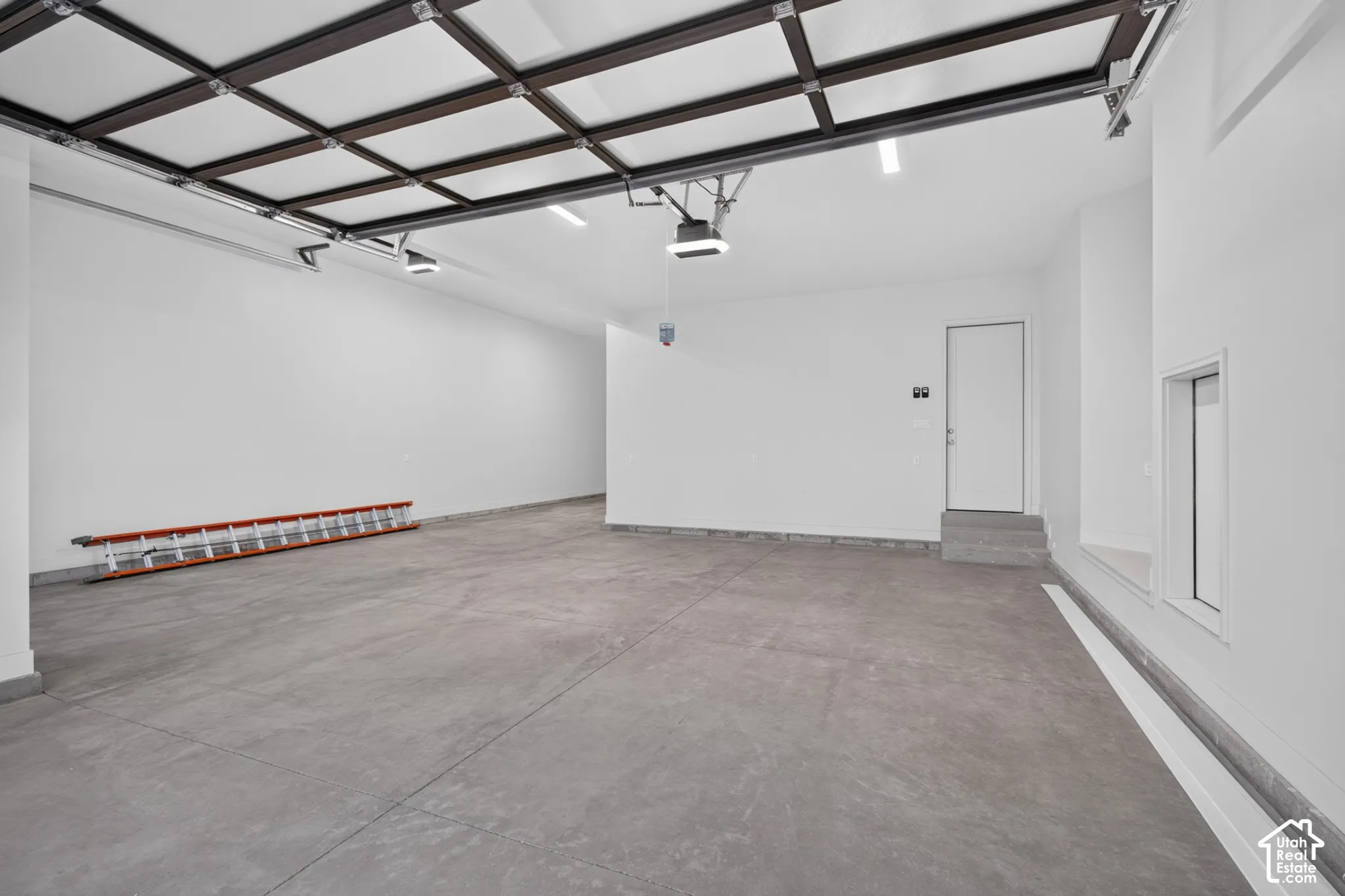 Finished garage featuring high-gloss concrete flooring, neutral wall finishes, integrated lighting, and a multi-pane glass panel garage door