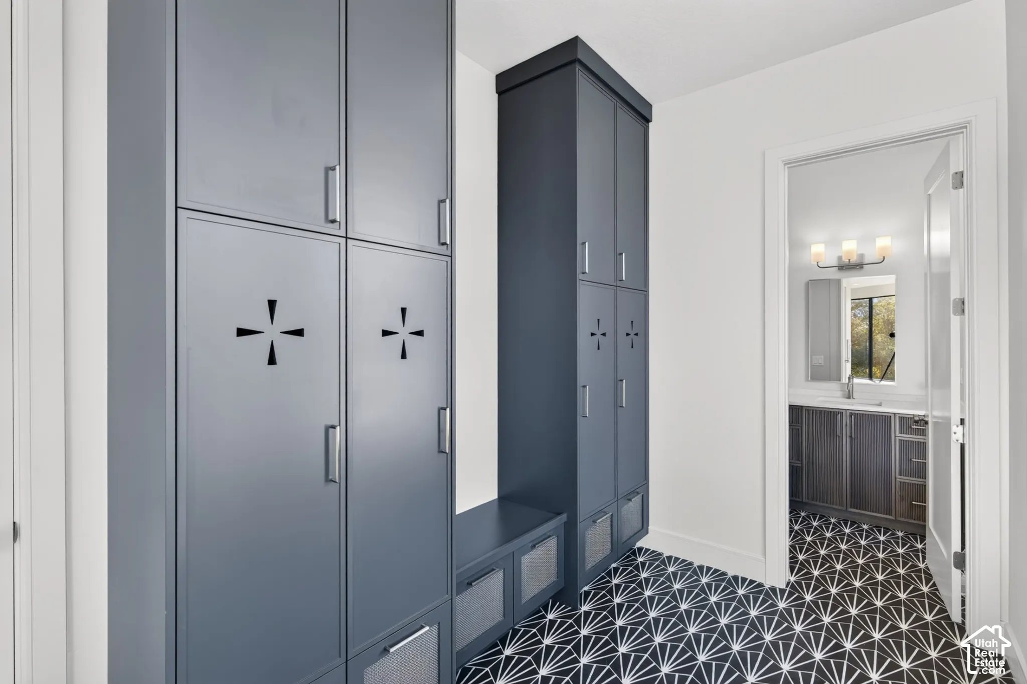 Built-in floor-to-ceiling storage lockers with matte metallic hardware, integrated bench seating, and patterned tile flooring