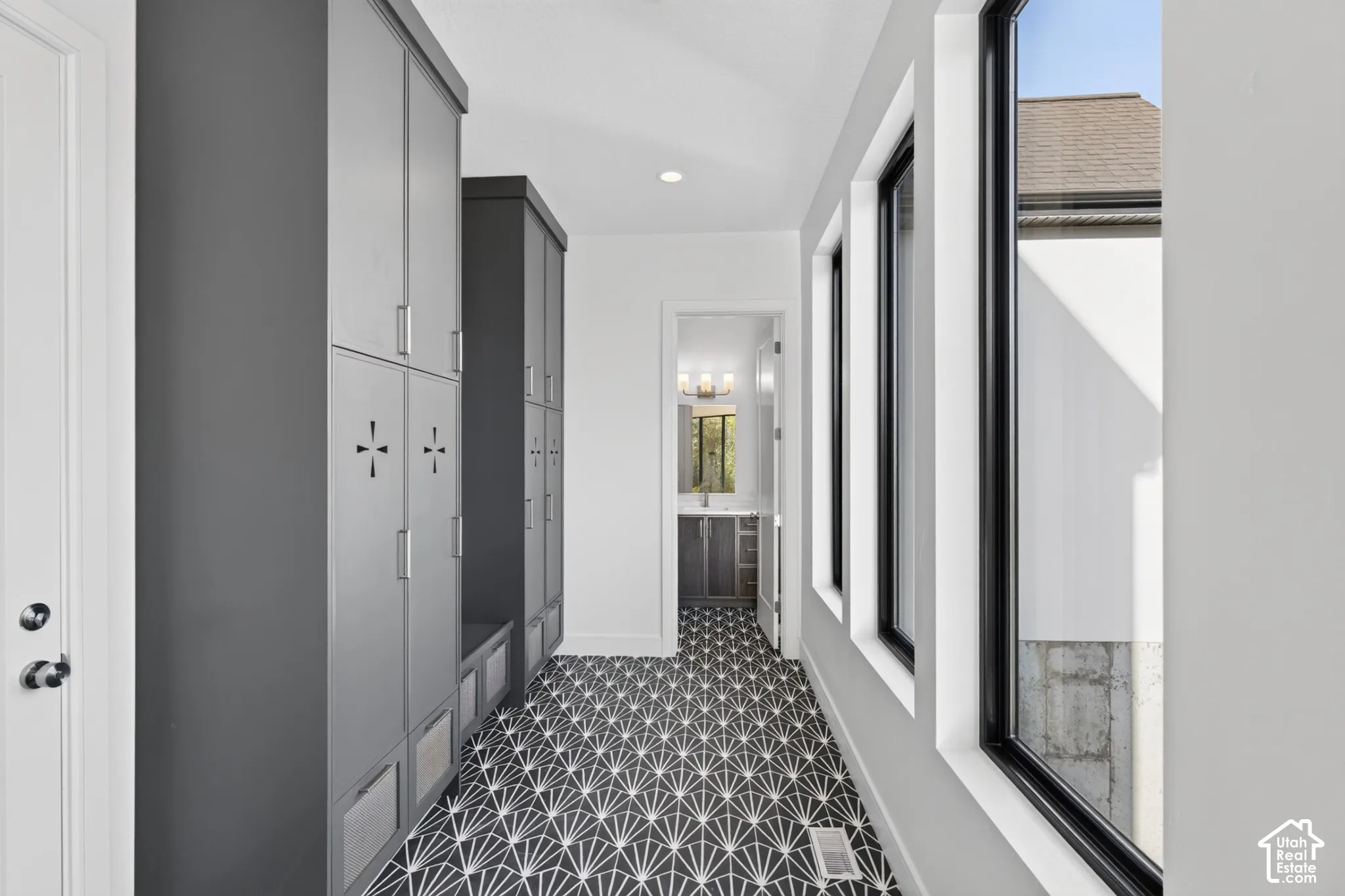 Floor-to-ceiling gray storage cabinetry, patterned geometric tile flooring, and tall windows with black frames