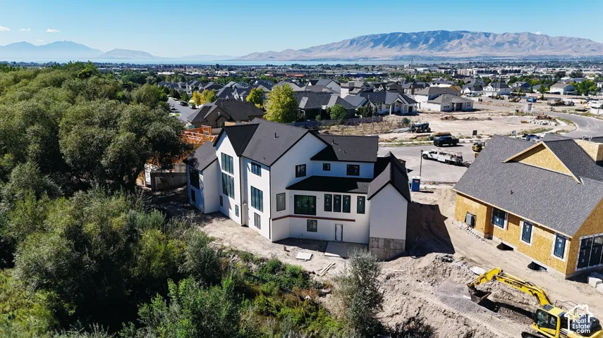 Two-story exterior featuring a white smooth-finish facade, dark roofline, expansive window placement, and mountain backdrop