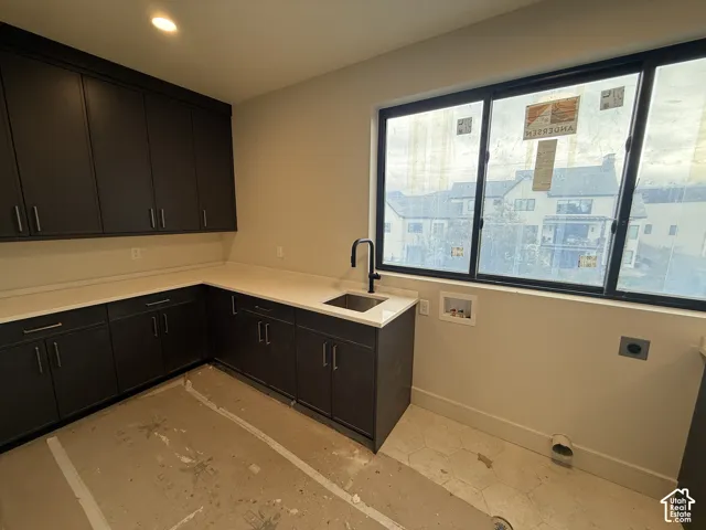 Dark cabinetry featuring clean-lined hardware, light-toned solid surface countertops, inset stainless steel sink with a matte black arched faucet, and multi-pane window with fixed upper sashes