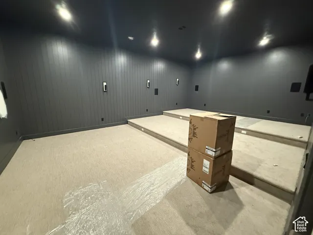 Multi-level tiered floor design featuring vertical paneled wall treatments, recessed ceiling lighting, and wall-mounted light fixtures