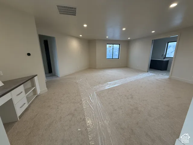 Loft featuring recessed lighting, neutral carpeting, and a built-in workstation with storage cabinetry and stone-finish countertop