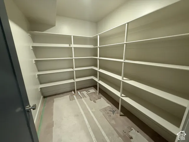 Walk-in storage area featuring floor-to-ceiling wrap-around white shelving