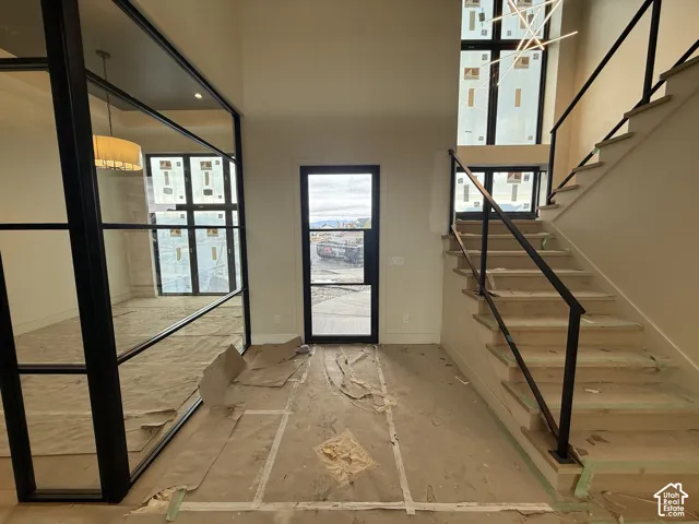 Foyer featuring a black-framed glass partition, a black steel entry door, a staircase with wood treads and a black metal railing, and multi-story windows