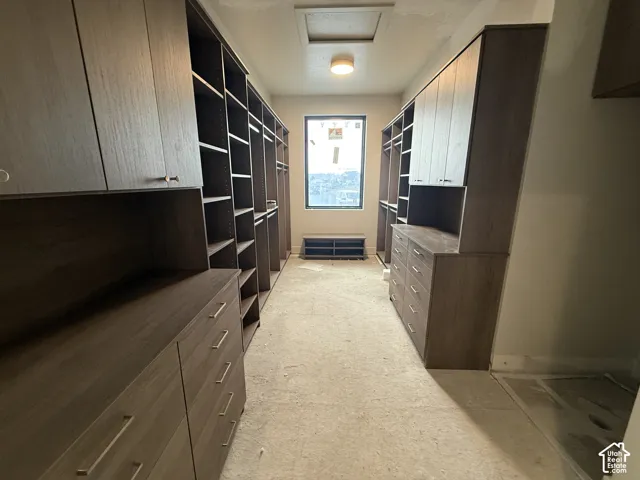 Custom wood-finish cabinetry featuring integrated shelving, floor-to-ceiling storage, built-in dresser drawers, and metal hardware
