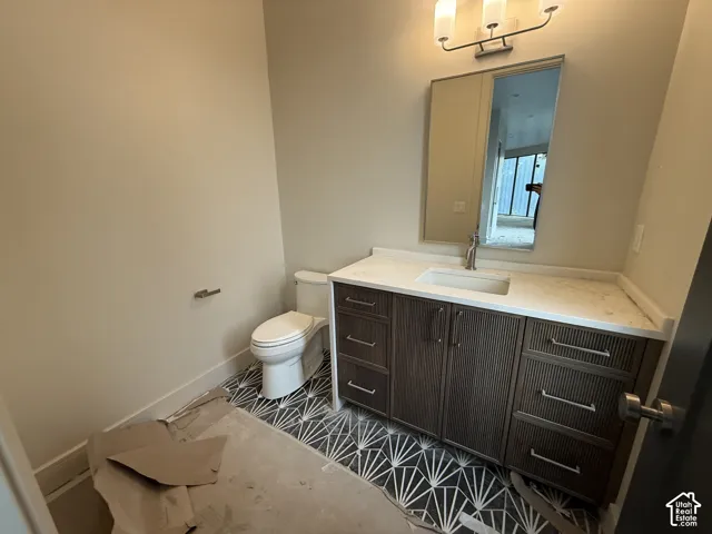 Bathroom featuring a vanity with reeded dark wood cabinetry, a light-toned solid surface countertop with an integrated rectangular sink, patterned floor tile, and a three-light wall-mounted fixture