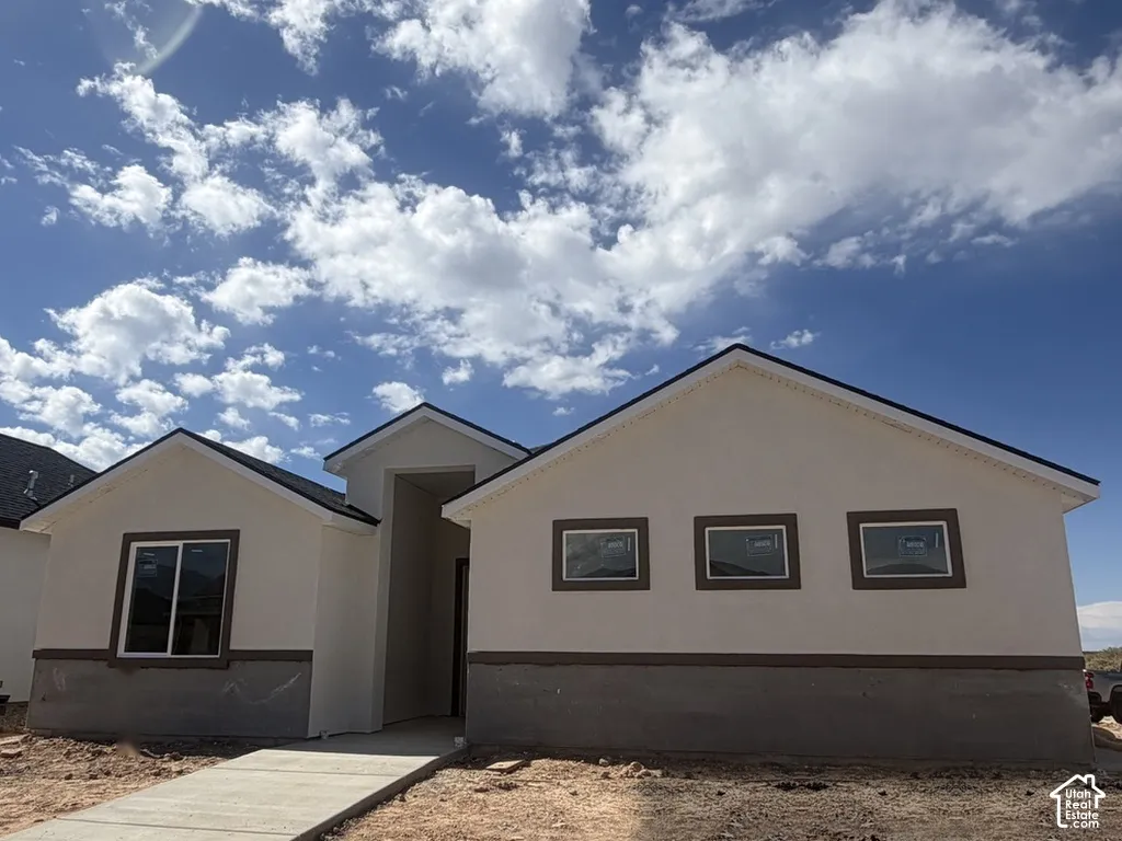 Single-story stucco exterior featuring a gabled roofline, contrast trim detailing, and a concrete walkway
