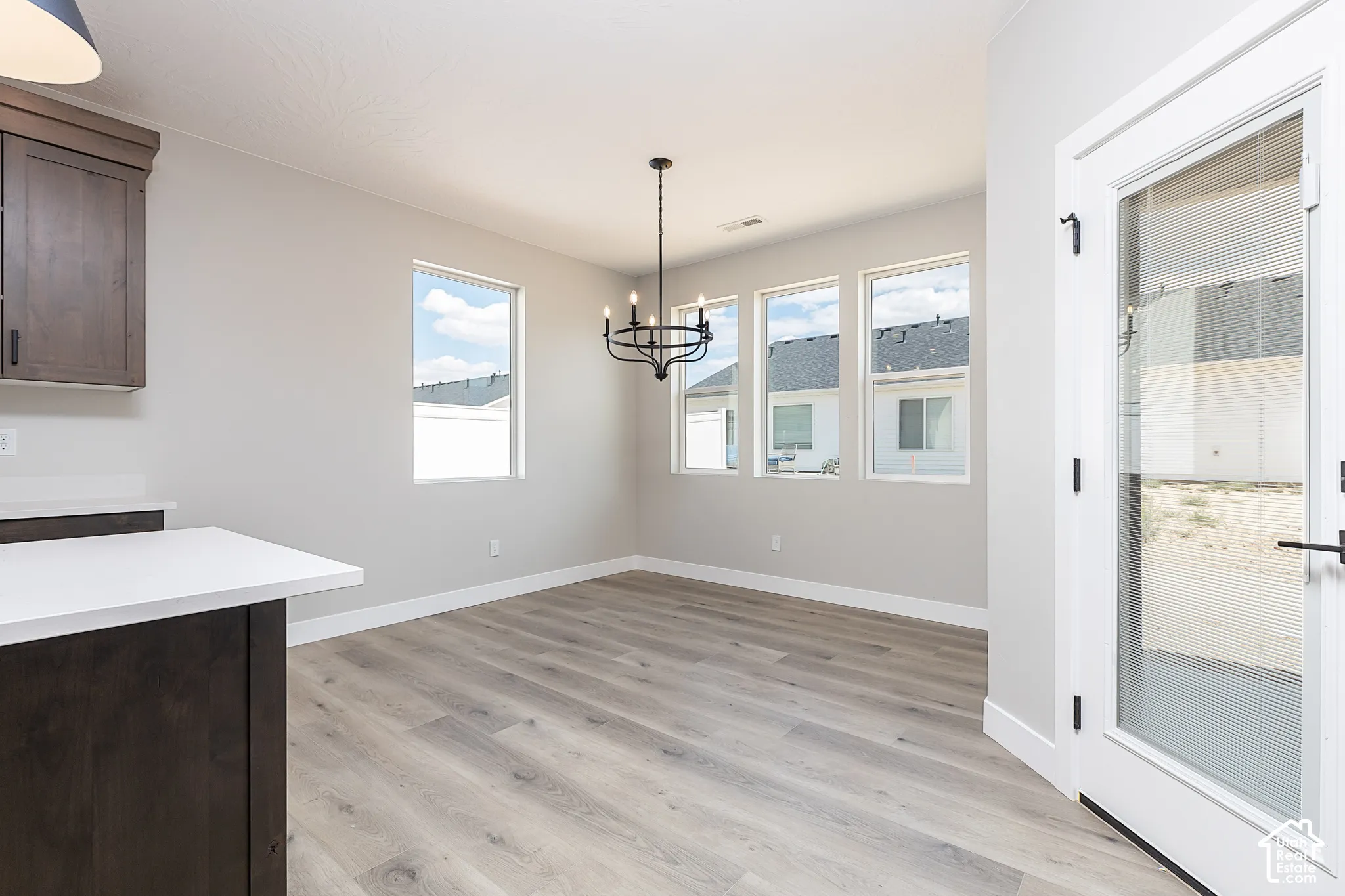 Dining area featuring wood-finish flooring, a multi-light candelabra chandelier, neutral wall tones, and glass-panel door