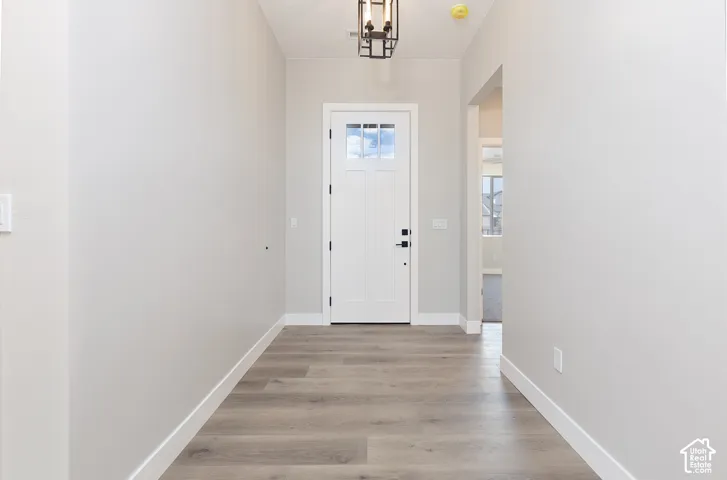 Entryway featuring wood-finish flooring, a white paneled front door with an integrated glass window, and a geometric pendant light fixture