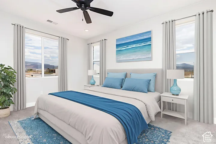 Neutral-toned carpeting, triple-window configuration with mountain scenery, and a matte black ceiling fan