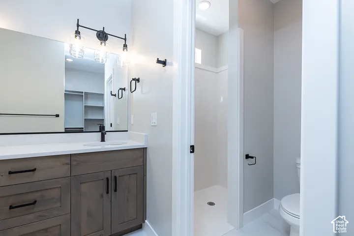 Bathroom featuring a wood-finish vanity with a light-toned countertop, matte black fixtures, an expansive wall mirror, and a standalone shower