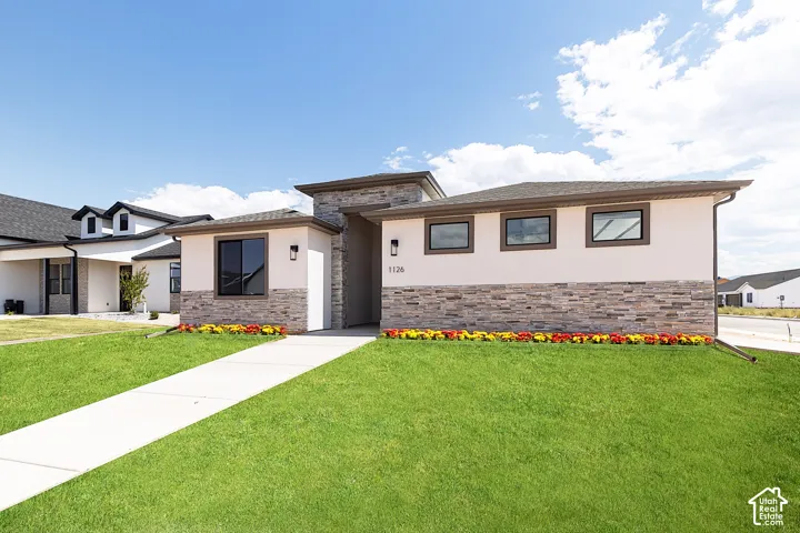 Contemporary exterior featuring a stucco finish, stone veneer accents, a concrete walkway, and low-profile rectangular windows