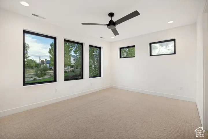 Neutral-toned carpeting, matte black framed windows, recessed ceiling lighting, and a modern ceiling fan