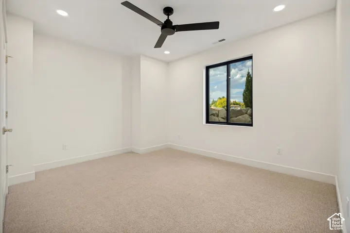 Neutral interior space featuring neutral wall-to-wall carpeting, recessed ceiling lighting, a matte black ceiling fan, and a large window with a black frame