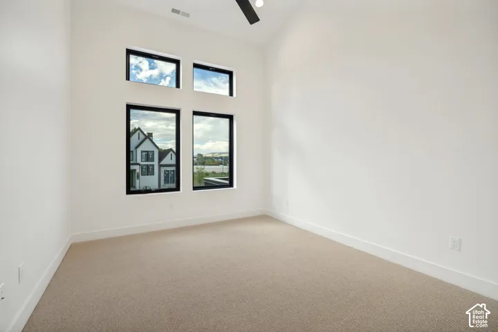 Vaulted ceiling room featuring neutral carpeting, expansive multi-pane windows with black frames, and a ceiling-mounted light fixture