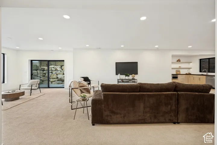 Open-concept interior featuring recessed lighting, sliding glass doors, built-in kitchen cabinetry with integrated shelving, and carpeted flooring