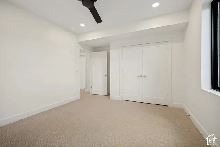 Neutral-toned wall-to-wall carpeting, double-door closet with satin-nickel hardware, matte black ceiling fan, and recessed lighting