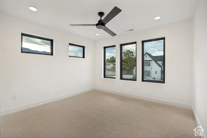 Interior room featuring high-contrast black-framed windows, neutral wall-to-wall carpeting, recessed ceiling lighting, and a matte black three-blade ceiling fan
