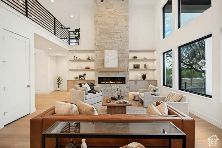 Double-height ceiling, floor-to-ceiling stone fireplace, custom built-in shelving, wood-finish flooring, and expansive windows