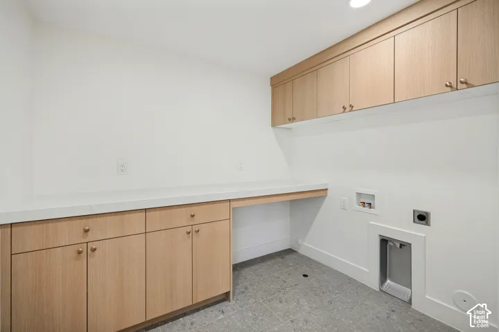 Custom wood-finish cabinetry featuring upper and lower storage units, stone-surface countertop, recessed lighting, and tile flooring