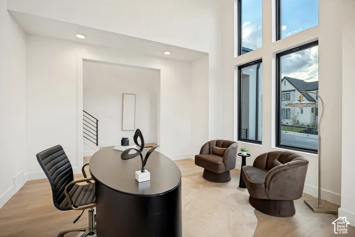 Double-height ceiling, tall black-framed windows, and wood-finish flooring