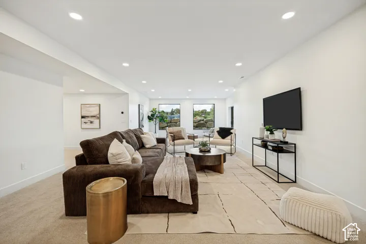 Open-concept room featuring neutral wall-to-wall carpeting, recessed ceiling lighting, and large windows with stone landscape exterior elements
