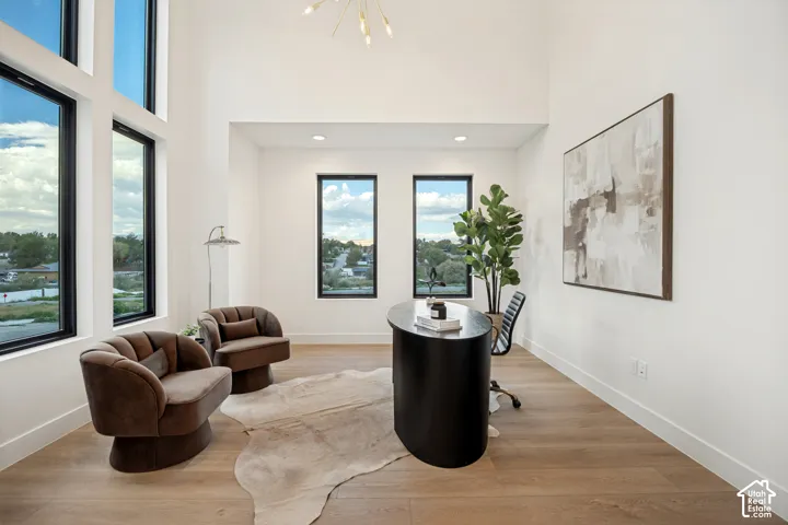 High-ceiling space featuring expansive floor-to-ceiling windows, wood-finish flooring, recessed lighting, and a multi-arm modern light fixture