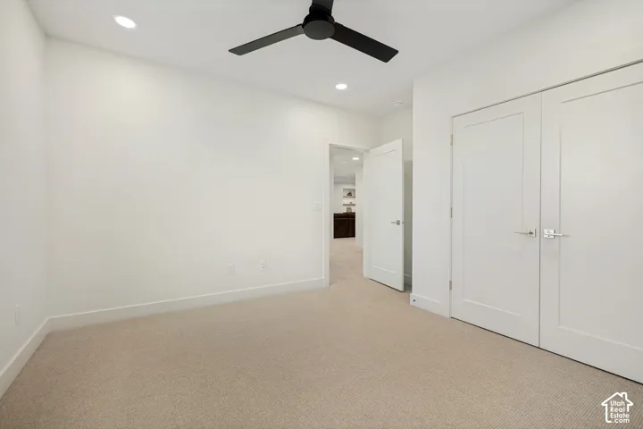Neutral-toned carpeting, matte black ceiling fan, recessed lighting, and double-panel closet doors