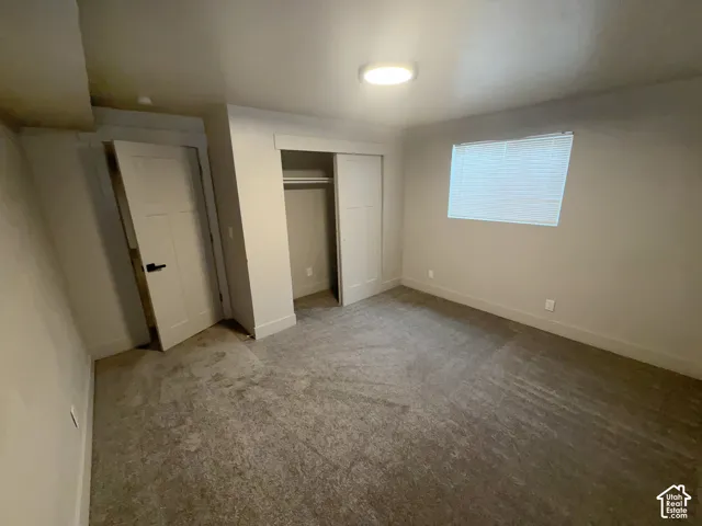 Recessed ceiling lighting, window with blinds, bi-fold closet doors, wall-to-wall carpeting, and a white interior door with black hardware