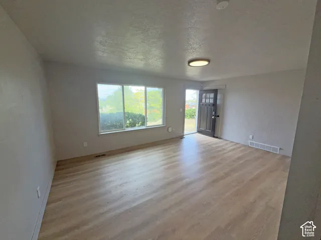 Wood-finish flooring, ample natural light, and a dark wood-paneled entry door